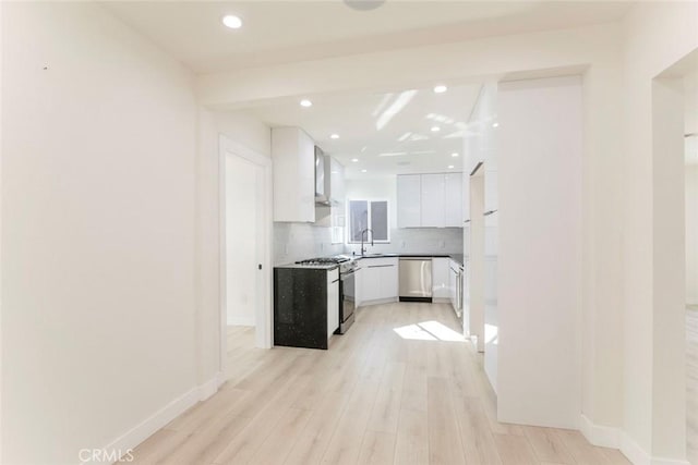 kitchen with decorative backsplash, light wood-style flooring, appliances with stainless steel finishes, white cabinets, and a sink