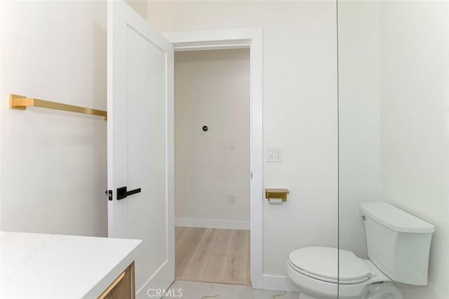 bathroom featuring toilet, vanity, baseboards, and wood finished floors