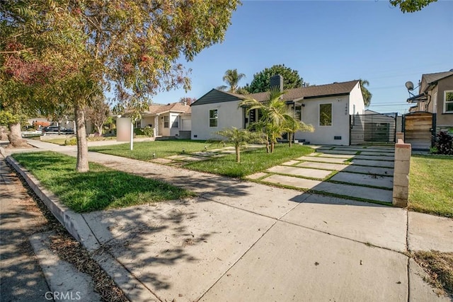 view of front of property with a front lawn, a gate, and stucco siding