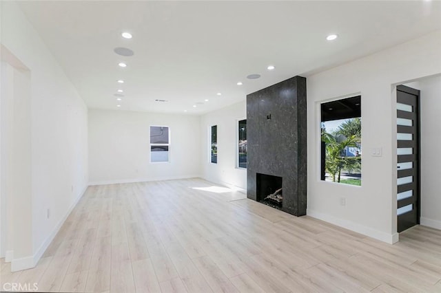 unfurnished living room with recessed lighting, light wood-type flooring, baseboards, and a fireplace