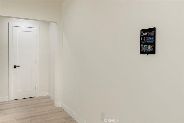 hall with light wood-type flooring and baseboards