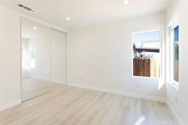 unfurnished bedroom with light wood finished floors, visible vents, recessed lighting, and a closet