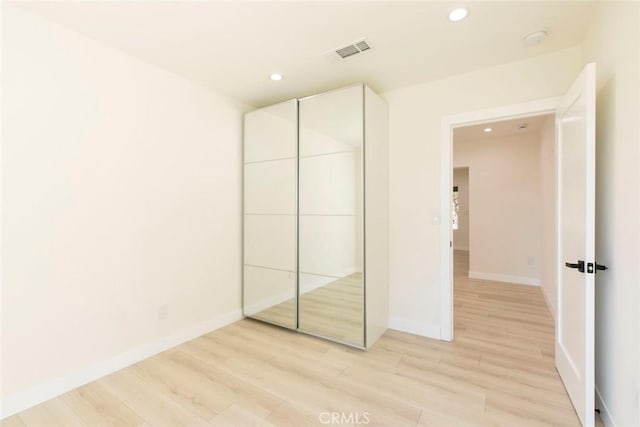 unfurnished bedroom with a closet, visible vents, recessed lighting, and light wood-style floors