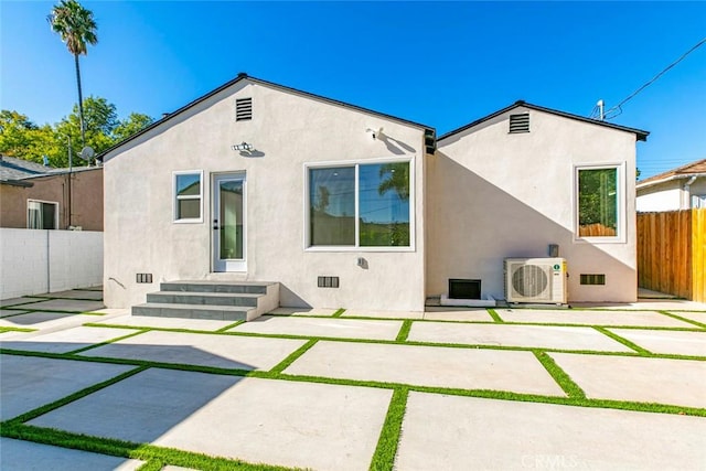 rear view of house featuring stucco siding, fence, a patio, and ac unit