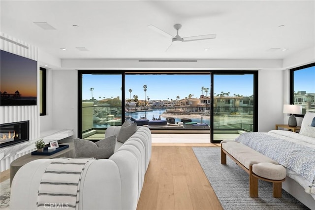 20 Balboa Cvs, Newport Beach, CA 92663 - bedroom featuring a ceiling fan, a glass covered fireplace, wood finished floors, and a water view