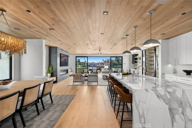20 Balboa Cvs, Newport Beach, CA 92663 - kitchen featuring wooden ceiling, open floor plan, light wood-type flooring, white cabinetry, and light stone counters