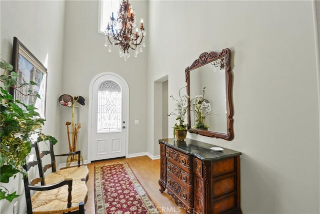 foyer entrance with a notable chandelier, light wood-style floors, and baseboards