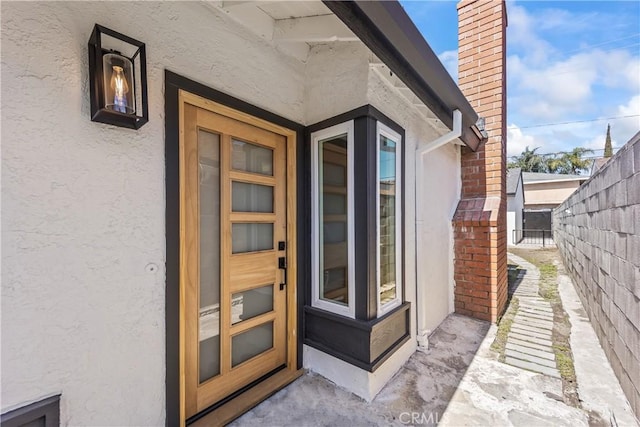 property entrance featuring stucco siding and fence