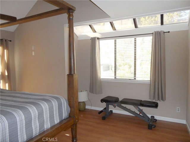 bedroom featuring baseboards, lofted ceiling, and wood finished floors