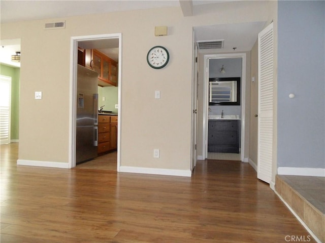 spare room featuring wood finished floors, visible vents, and baseboards