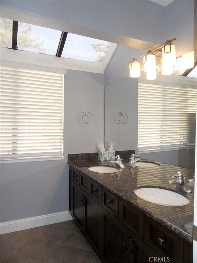 bathroom with double vanity, baseboards, and a sink