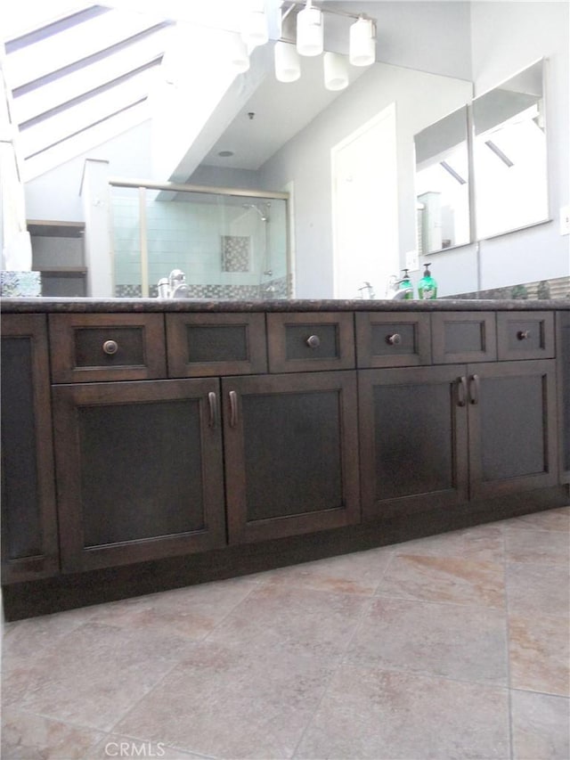 bathroom with lofted ceiling, vanity, and a shower stall