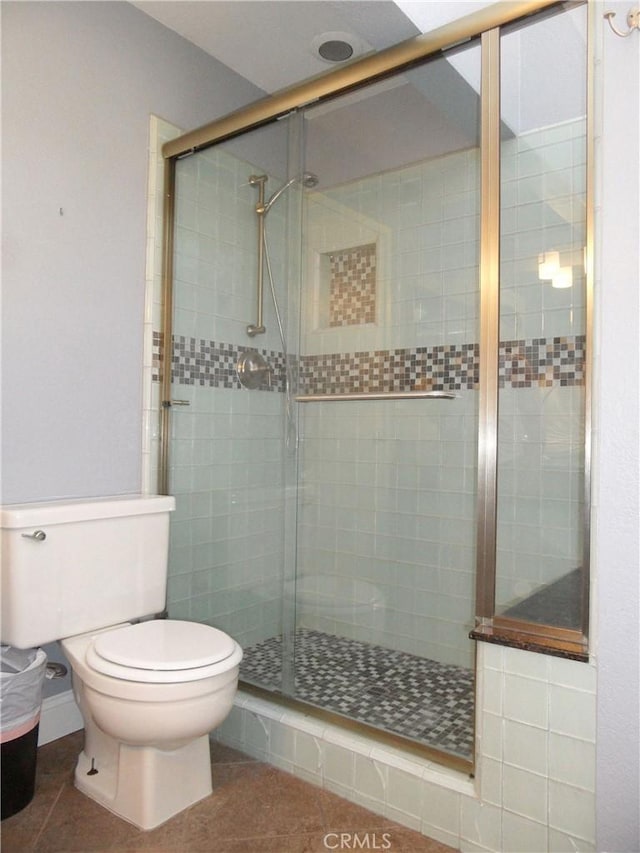 bathroom with tile patterned floors, toilet, and a shower stall