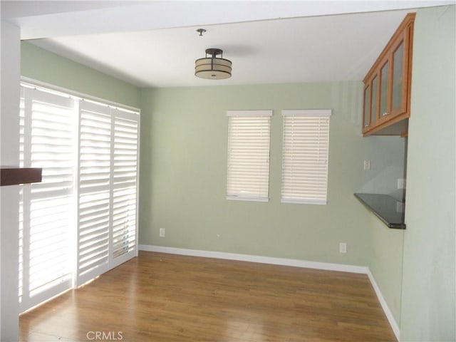 unfurnished dining area with baseboards and wood finished floors