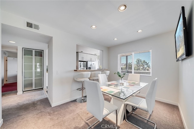 dining space with light colored carpet, visible vents, and baseboards