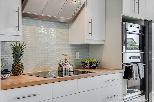 kitchen with ventilation hood, black electric cooktop, double oven, and butcher block counters