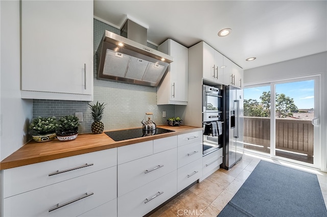 kitchen with decorative backsplash, wall chimney range hood, stainless steel appliances, and butcher block counters