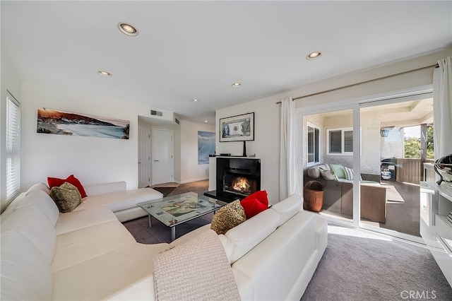 living room with recessed lighting, visible vents, and a warm lit fireplace