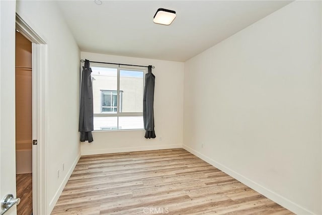 unfurnished room with baseboards and light wood finished floors