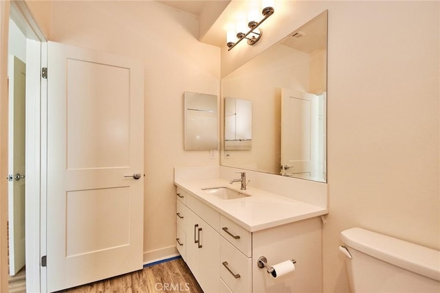 half bathroom featuring vanity, toilet, and wood finished floors