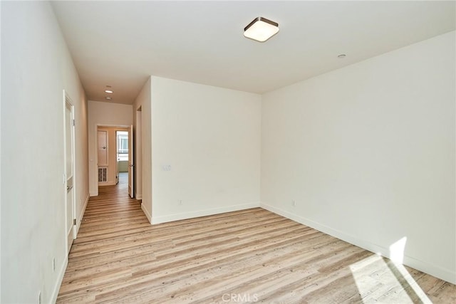 spare room with light wood-style floors and baseboards