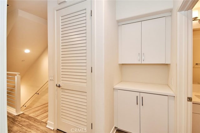 hall with an upstairs landing and light wood-style flooring