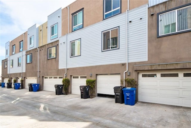 view of building exterior with a residential view, driveway, and an attached garage