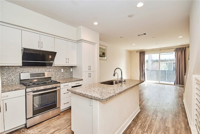 kitchen featuring decorative backsplash, light wood-style floors, gas stove, white cabinetry, and a sink