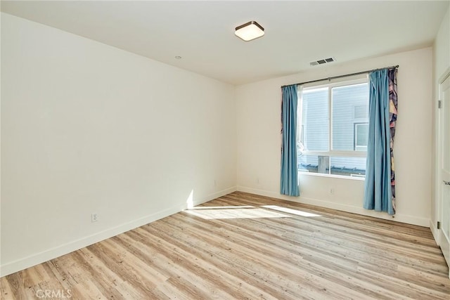 unfurnished room with baseboards, visible vents, and light wood-type flooring