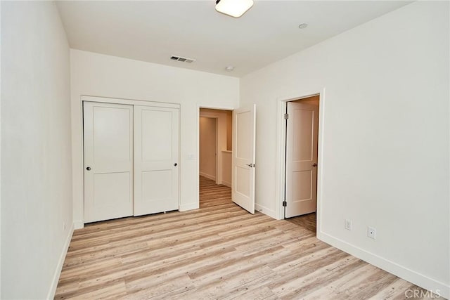 unfurnished bedroom with a closet, visible vents, baseboards, and light wood-style floors