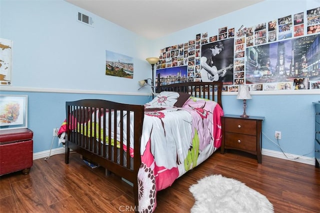 bedroom featuring visible vents, baseboards, and wood finished floors