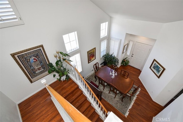 dining space with high vaulted ceiling, baseboards, and wood finished floors