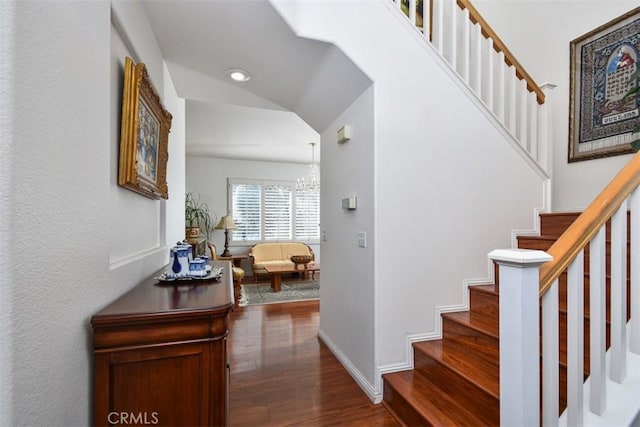 staircase featuring baseboards, an inviting chandelier, wood finished floors, and vaulted ceiling