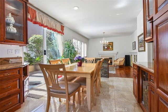 dining area featuring a notable chandelier and a warm lit fireplace