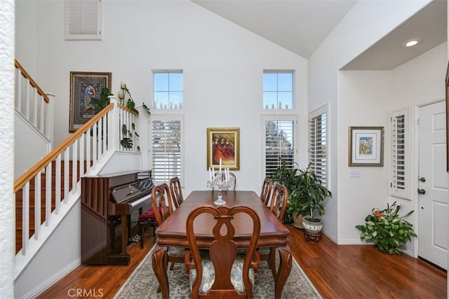 dining area with stairway, wood finished floors, baseboards, and high vaulted ceiling