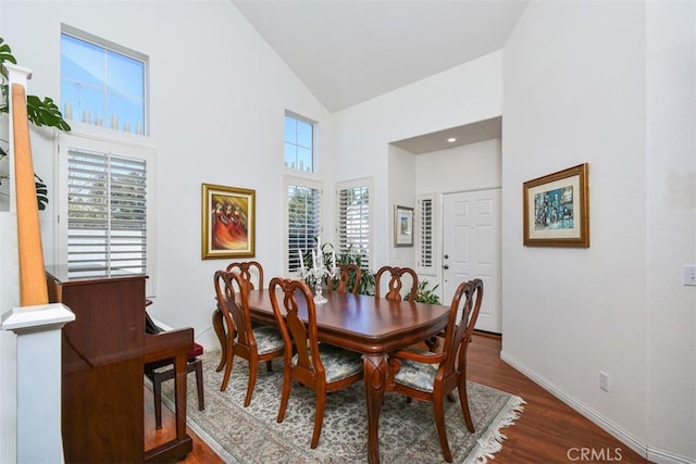 dining area featuring high vaulted ceiling, baseboards, and dark wood-style flooring