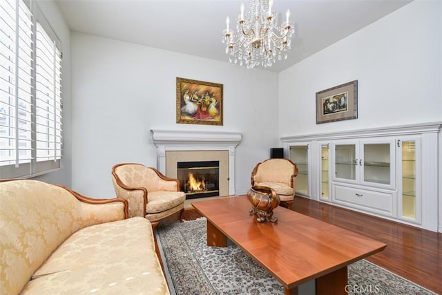 sitting room featuring a glass covered fireplace, an inviting chandelier, and wood finished floors