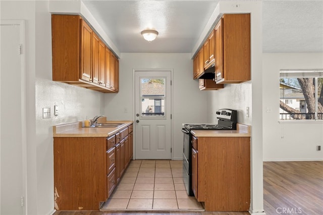 kitchen featuring a sink, brown cabinets, light countertops, and electric stove