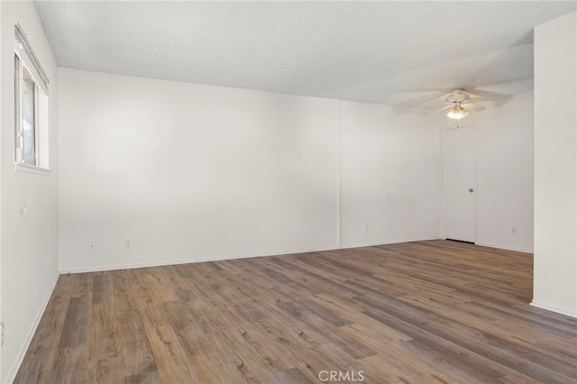 spare room with ceiling fan, wood finished floors, and a textured ceiling