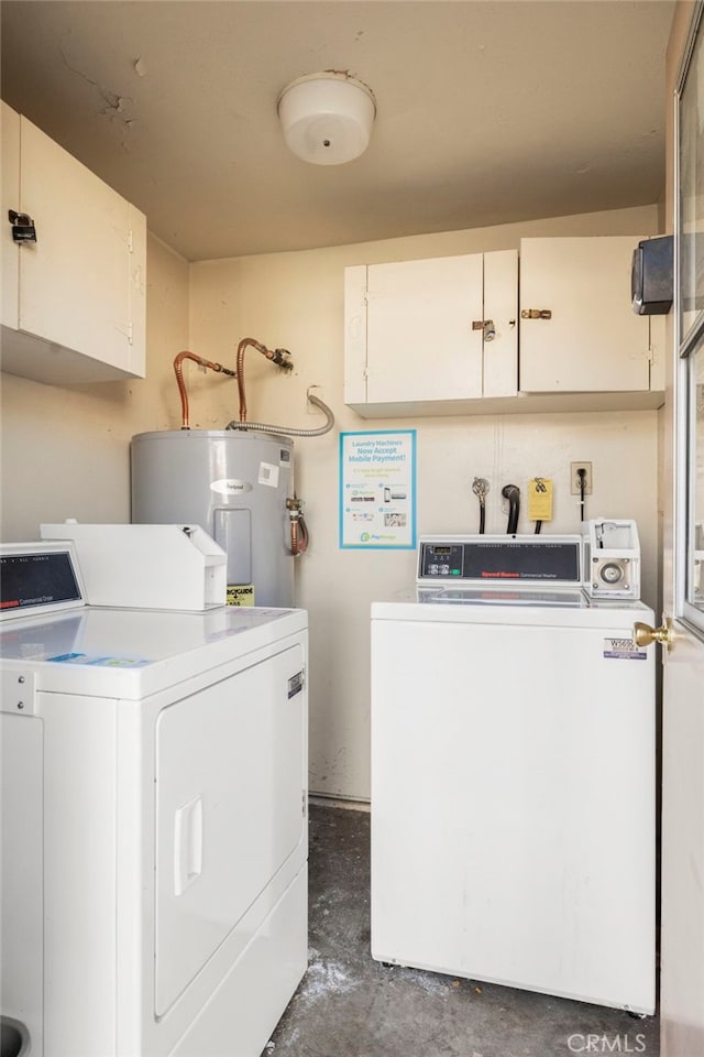 clothes washing area with cabinet space, separate washer and dryer, and electric water heater