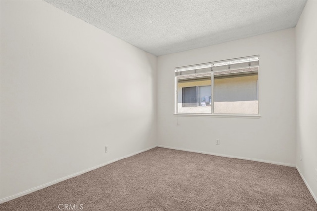 carpeted spare room with baseboards and a textured ceiling