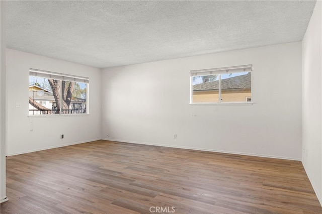 spare room with a textured ceiling, baseboards, and wood finished floors