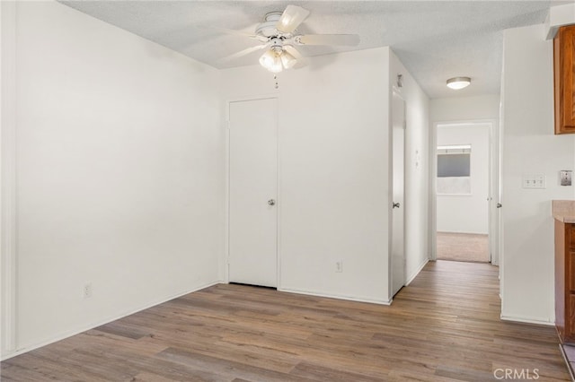 empty room featuring baseboards, a textured ceiling, ceiling fan, and wood finished floors