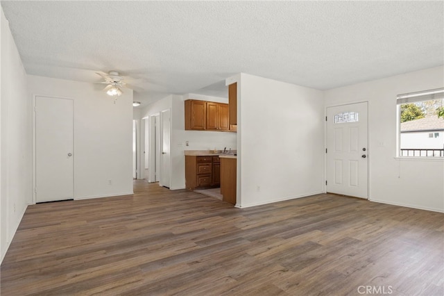 unfurnished living room featuring a textured ceiling, wood finished floors, and a ceiling fan