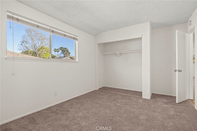 unfurnished bedroom with a closet, carpet flooring, a textured ceiling, and baseboards