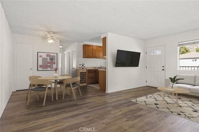 dining area featuring beverage cooler, a textured ceiling, ceiling fan, and dark wood-style flooring