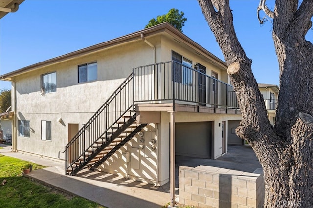 view of front of property featuring stairway, a garage, and stucco siding