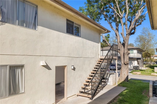 view of side of home featuring stairway and stucco siding