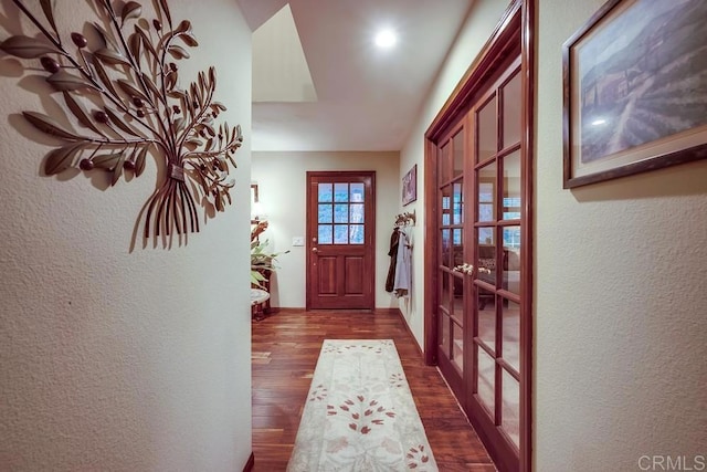 doorway with french doors, dark wood-style floors, and a textured wall