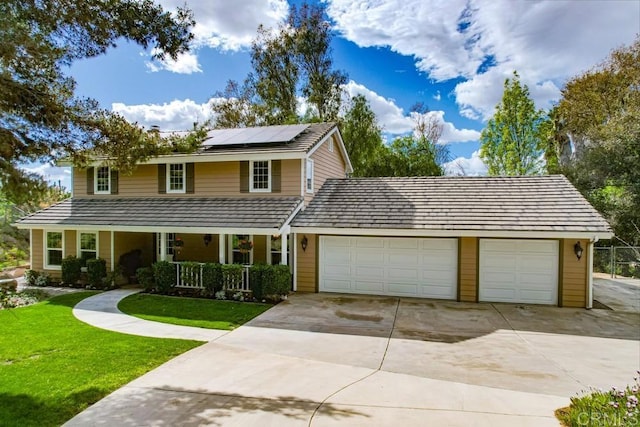 view of front of property featuring solar panels, a porch, a front yard, a garage, and driveway